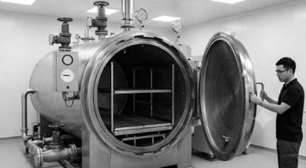 Profissional de engenharia clínica realiza teste hidrostático para Inspeção em Autoclave cilíndrica de grande porte em ambiente hospitalar.